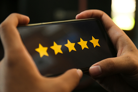 Attractive hands giving five stars rating on a smart phone